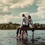 Romantic scene of a couple sitting on a jetty over a lake in Lithuania, enjoying the serene outdoors.
