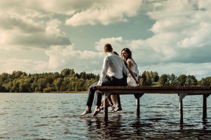 Romantic scene of a couple sitting on a jetty over a lake in Lithuania, enjoying the serene outdoors.