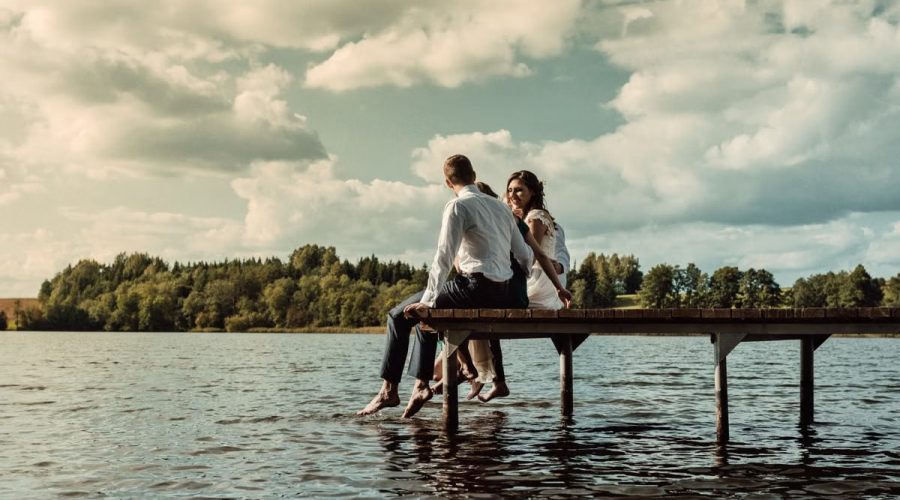 Romantic scene of a couple sitting on a jetty over a lake in Lithuania, enjoying the serene outdoors.